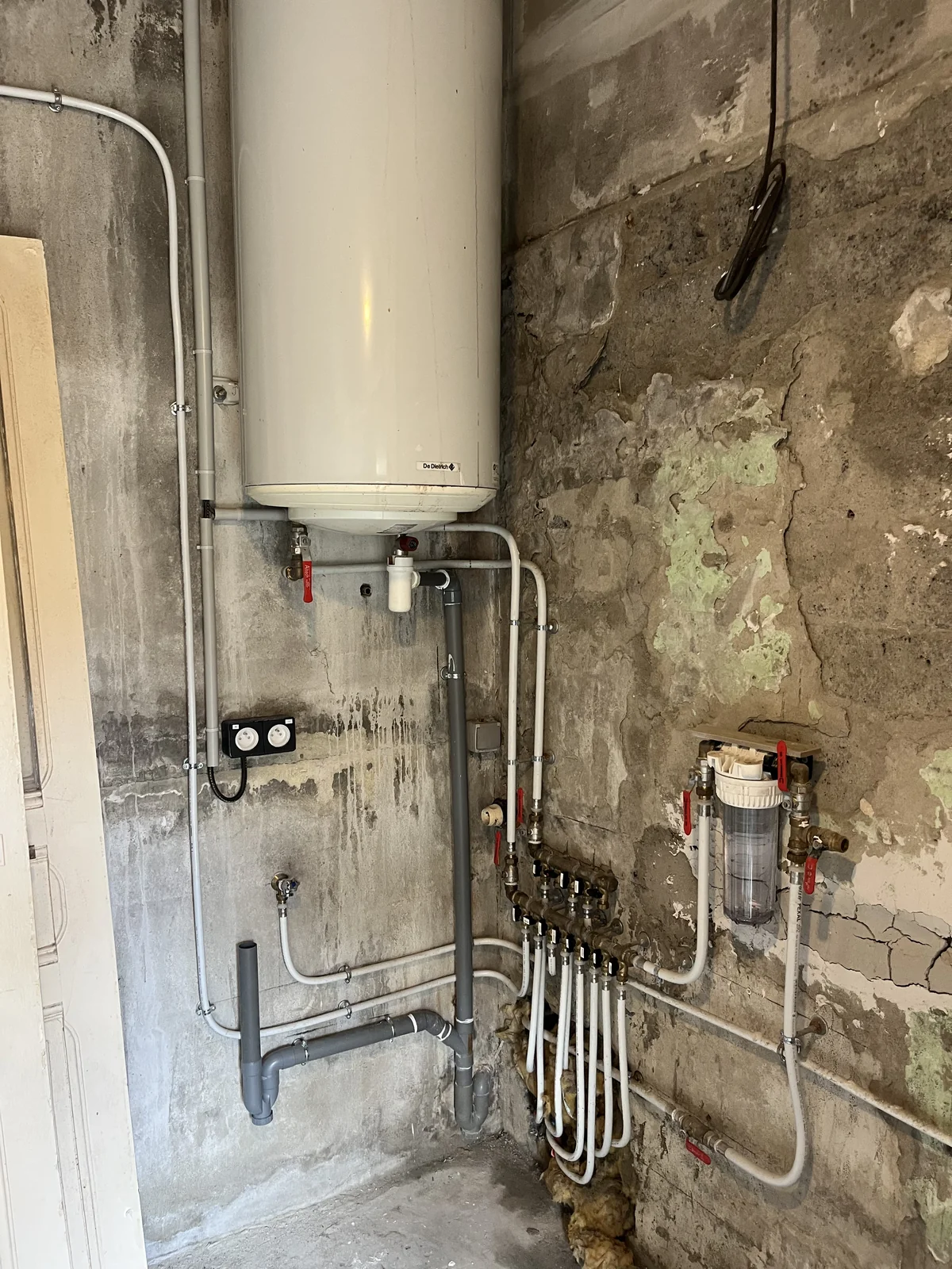 Installation sanitaire en multicouche à Arles : clarinettes de distribution avec vannes d'arrêt sous un chauffe-eau mural.