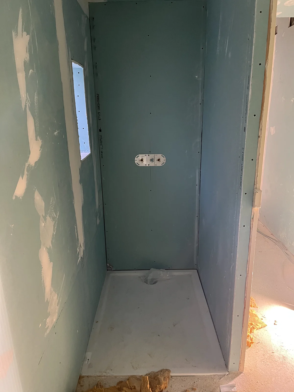 Espace douche en cours de préparation, avec receveur, parois et sorties de robinetterie visibles.